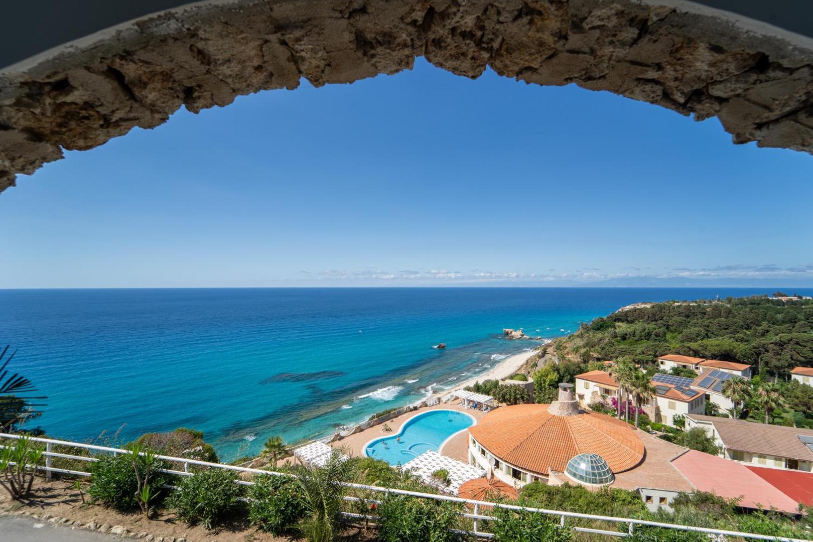 Villagio Marco Polo viesnīcas komplekss Kalabrijā ar āra baseinu un skatu uz pludmali — arhitektūra un piekrastes ainava