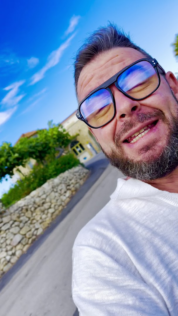 Viesnīcas Villagio Marco Polo viesis saulainā dienā pie akmens mūra sienas un zaļumiem Kalabrijas reģionā Itālijā
