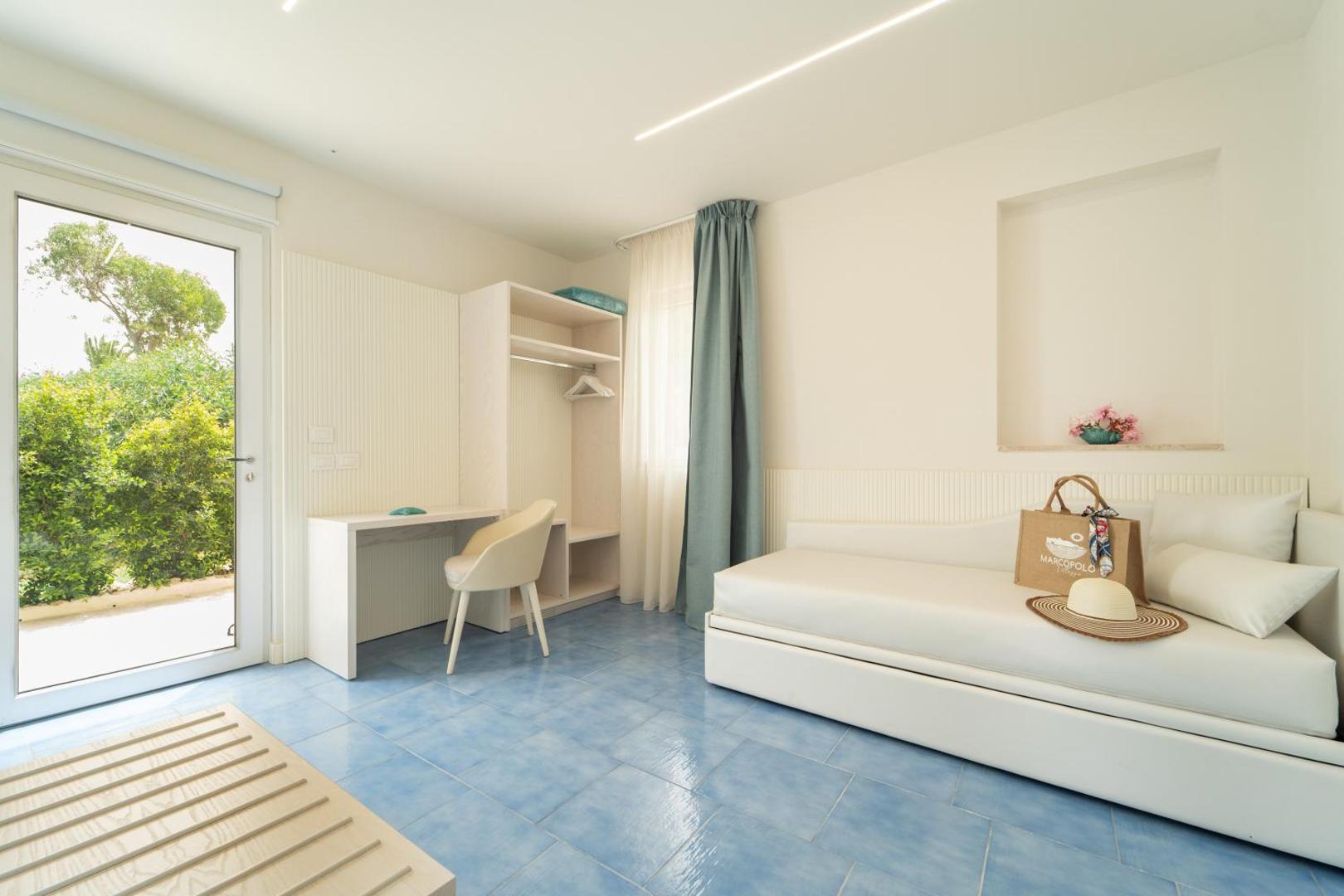 Villagio Marco Polo numura interjers ar dīvānu, drēbju skapi un izeju uz dārzu piekrastes viesnīcā Itālijā