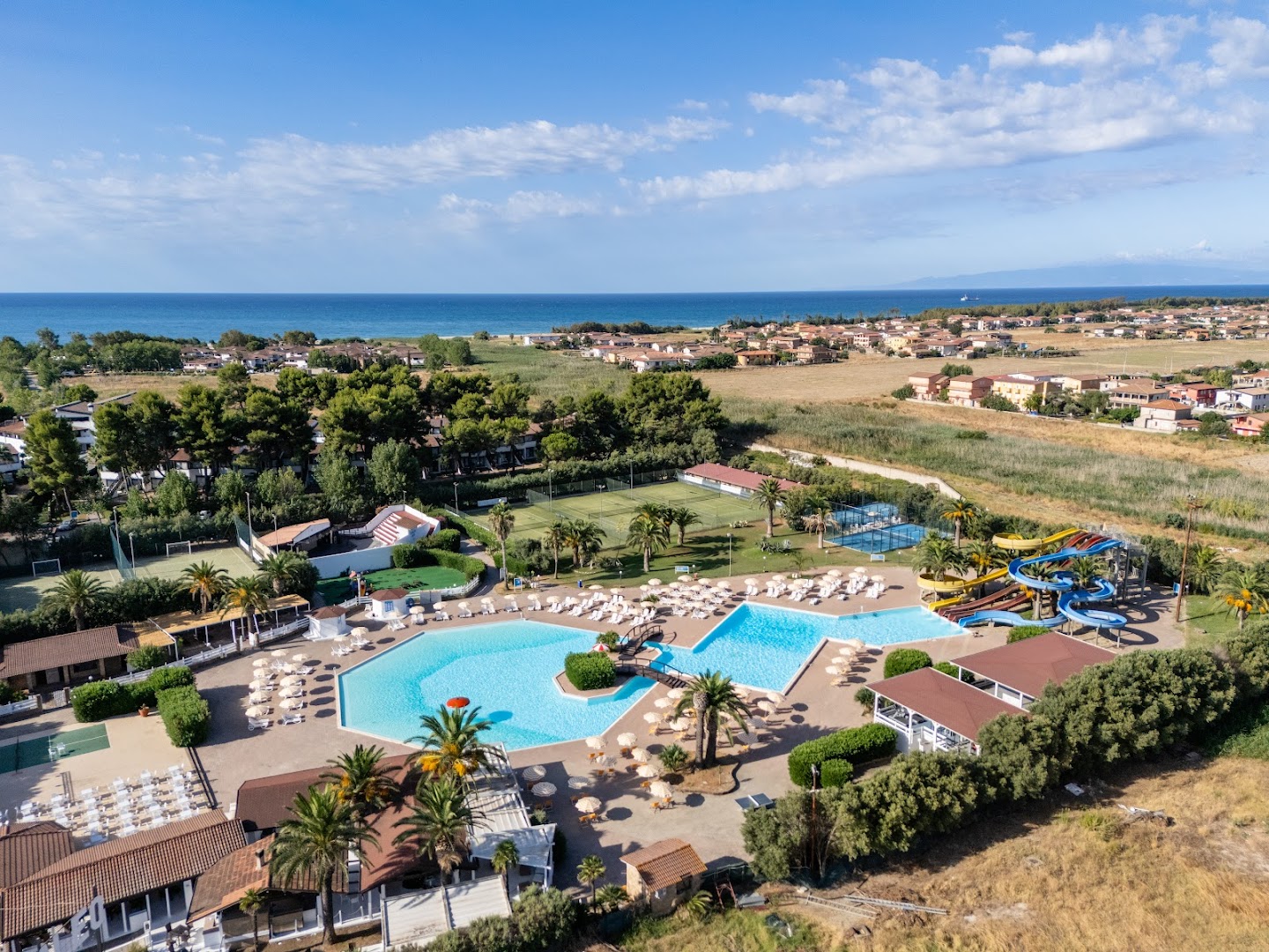 Futura Club Porto Kaleo panorāmas skats uz plašo baseinu kompleksu, ūdens slidkalniņiem un sporta laukumiem piekrastē Kalabrijā, Itālijā.