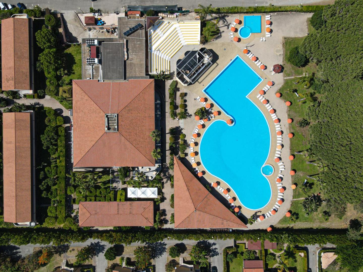 Futura Club La Praya skats no putna lidojuma uz lielo āra baseinu, saulessargiem un viesnīcas korpusiem Kalabrijā, Itālijā.