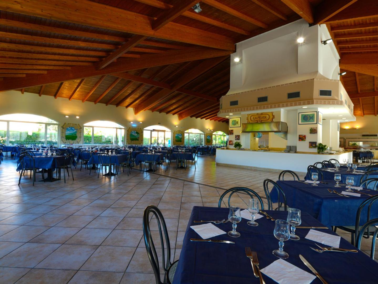 Futura Club La Praya restorāna iekštelpas ar koka griestu sijām, klātiem galdiem un bufetes zonu Kalabrijā, Itālijā
