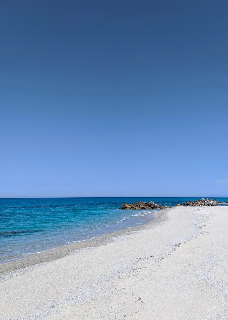 Midenza Seaside & Nature Retreat privātā smilšu pludmale ar gaišām smiltīm un zilu jūru zem skaidrām debesīm.
