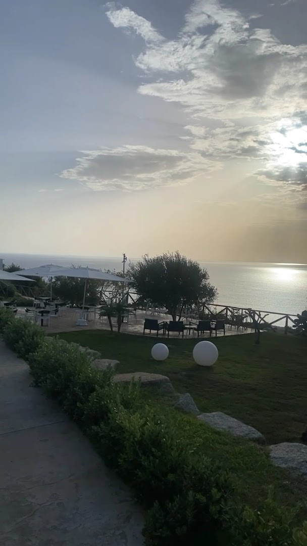 Midenza Seaside & Nature Retreat āra terase saulrietā ar skatu uz jūru Kalabrijā, Itālijā — atpūtas zona ar dārza mēbelēm un zālāju