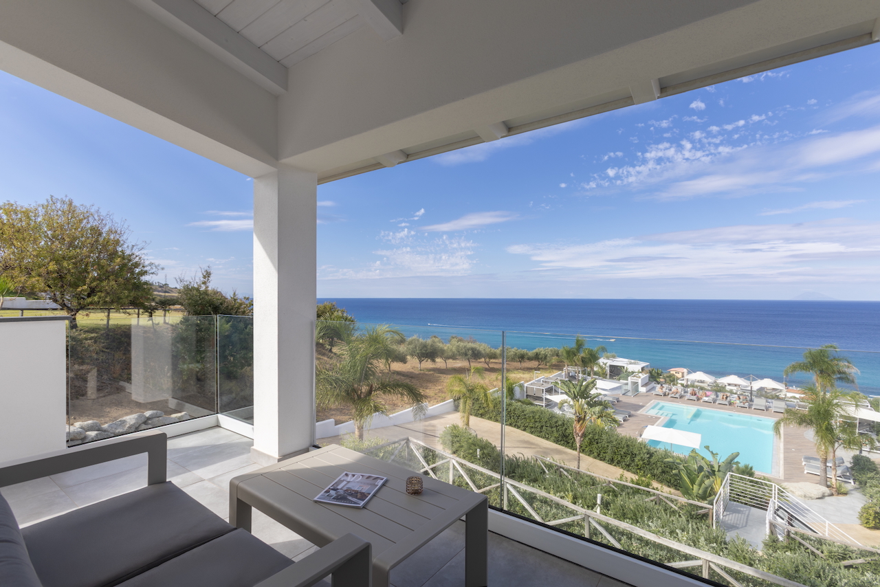 Midenza Seaside & Nature Retreat numura terase ar skatu uz Jonijas jūru un baseinu Kalabrijā, Itālijā — atpūtas zona ar dīvānu