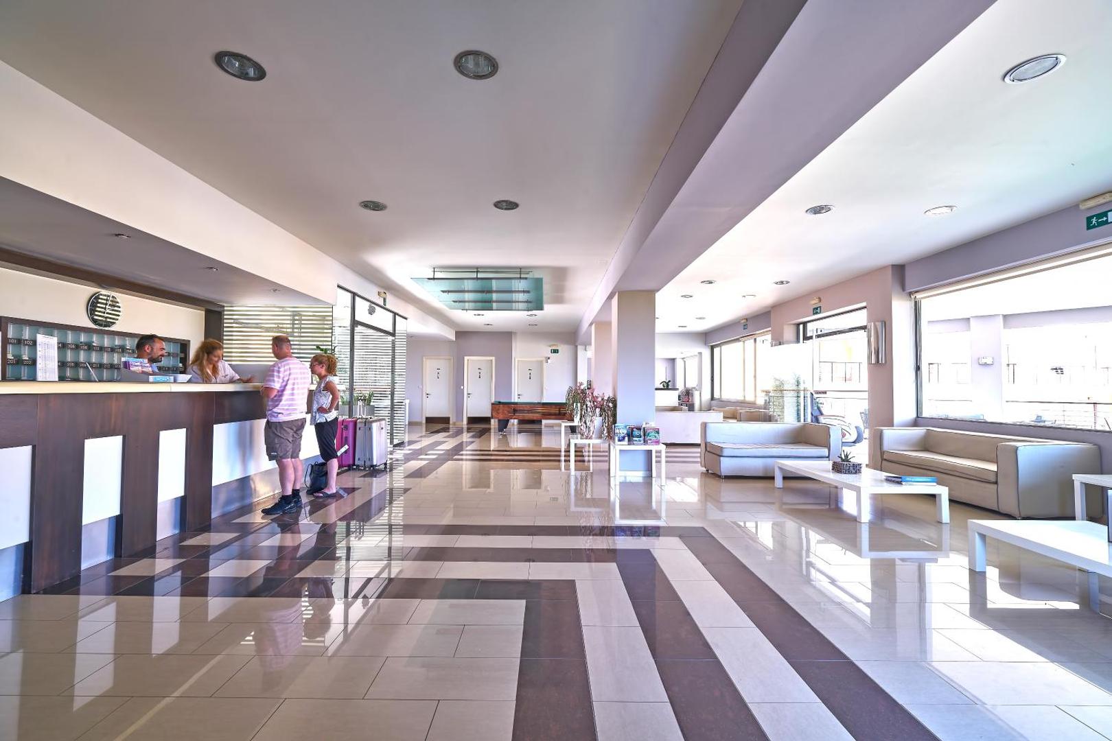 Sunrise Village Hotel plašais lobby un recepcijas zona ar atpūtas dīvāniem un modernu apgaismojumu — viesu uzņemšanas telpa