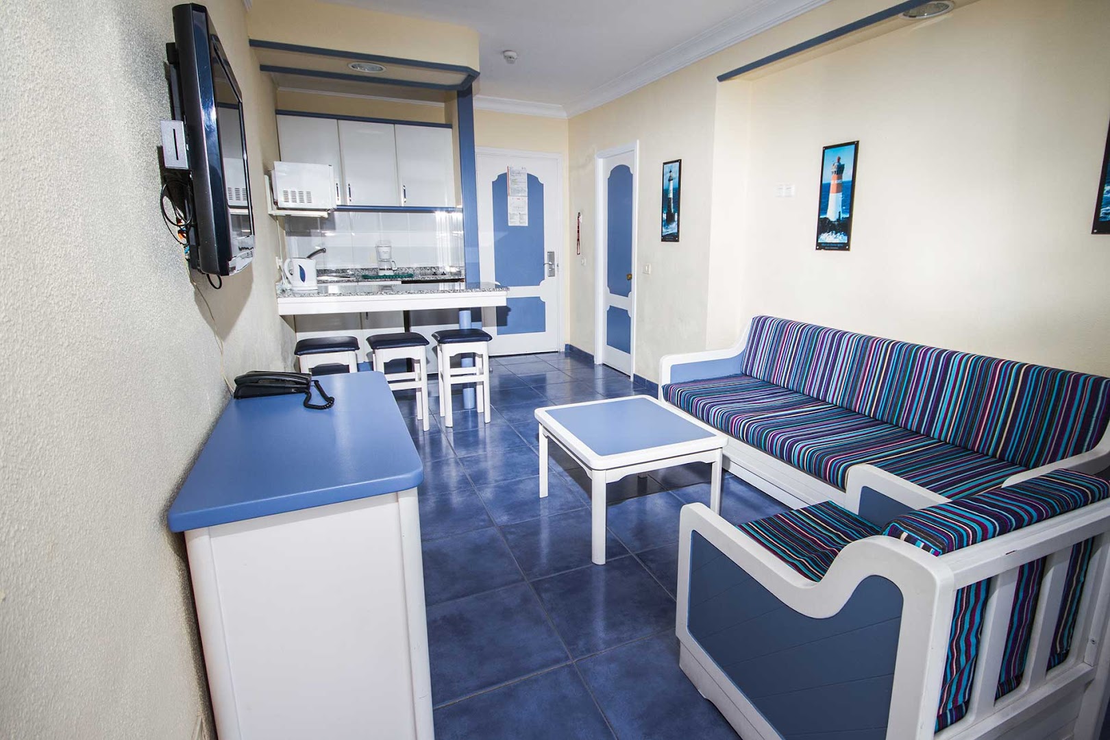 Servatur Puerto Azul Hotel numurs ar virtuves zonu un ziliem akcentiem Grankanārijā — viesistaba ar dīvānu, galdiņu un brokastu bāru