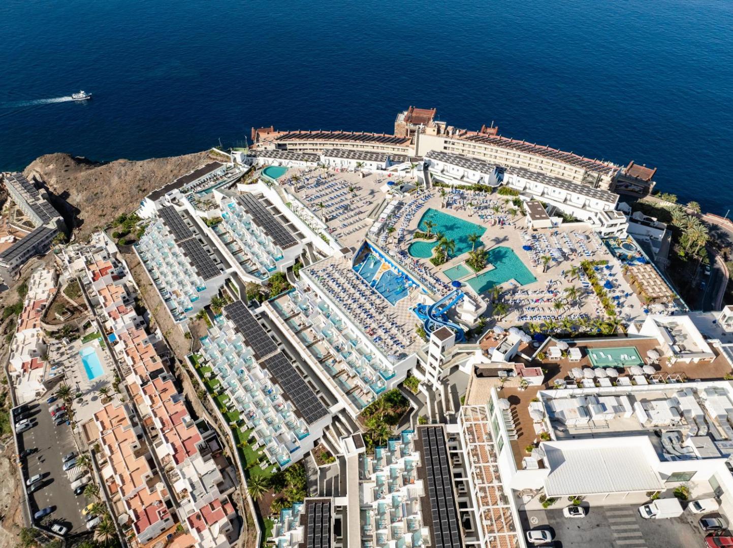 Servatur Puerto Azul Hotel arhitektūra no putna lidojuma Puerto de Mogan piekrastē — viesnīcas korpusi, baseini un ūdens slidkalniņi