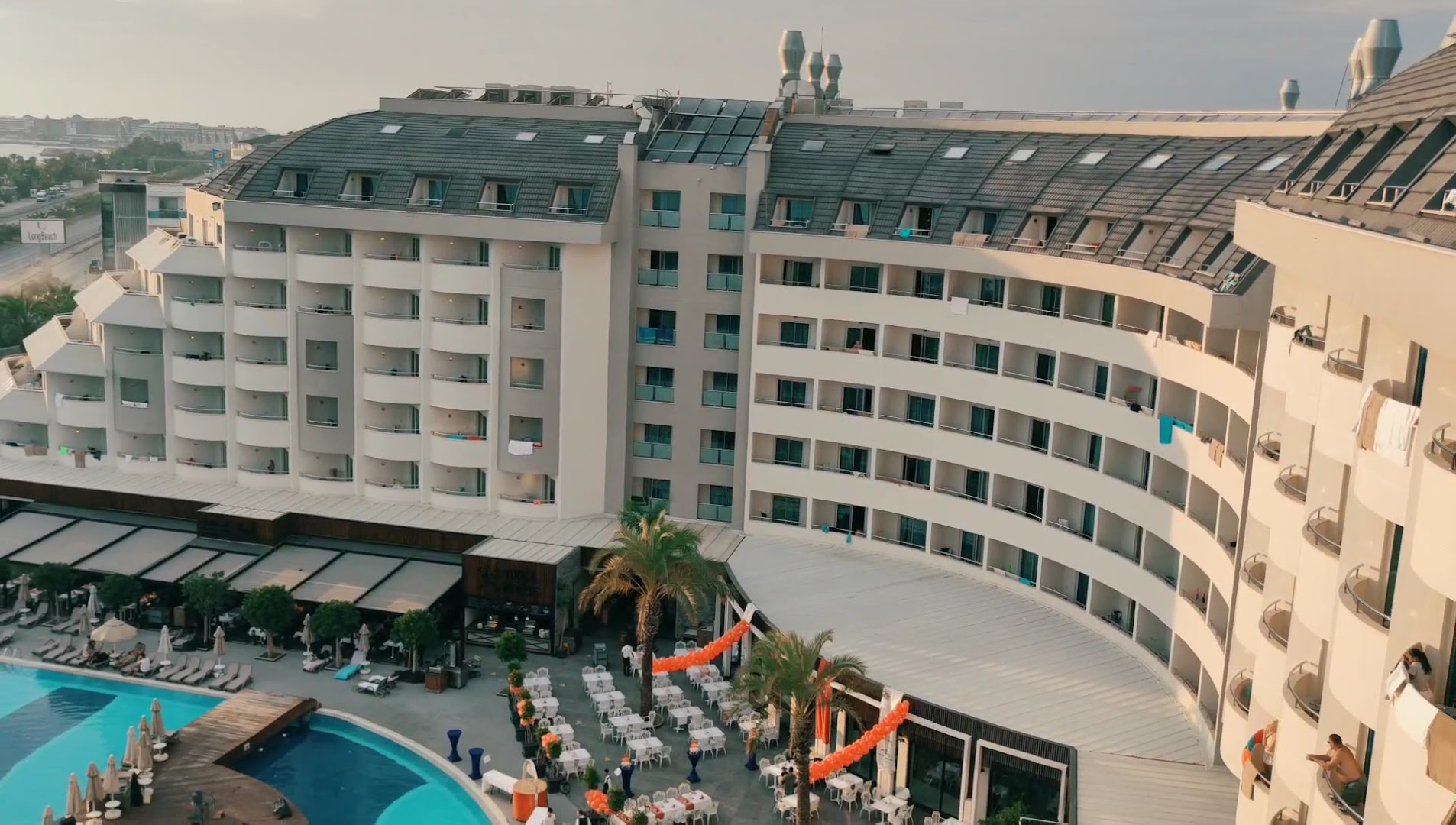 Long Beach Resort viesnīcas korpuss ar balkoniem, āra baseinu un restorāna terasi pasākuma sagatavošanas laikā