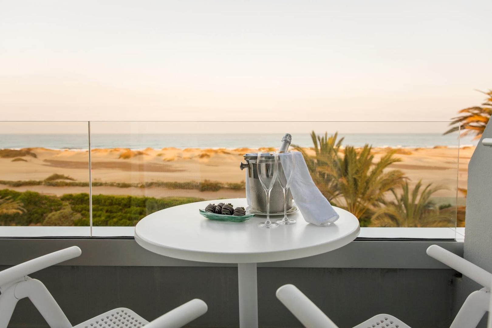 Santa Mónica Suites Hotel numura terase ar skatu uz Maspalomas kāpām Grankanārijā — galds ar šampanieti un zemenēm šokolādē