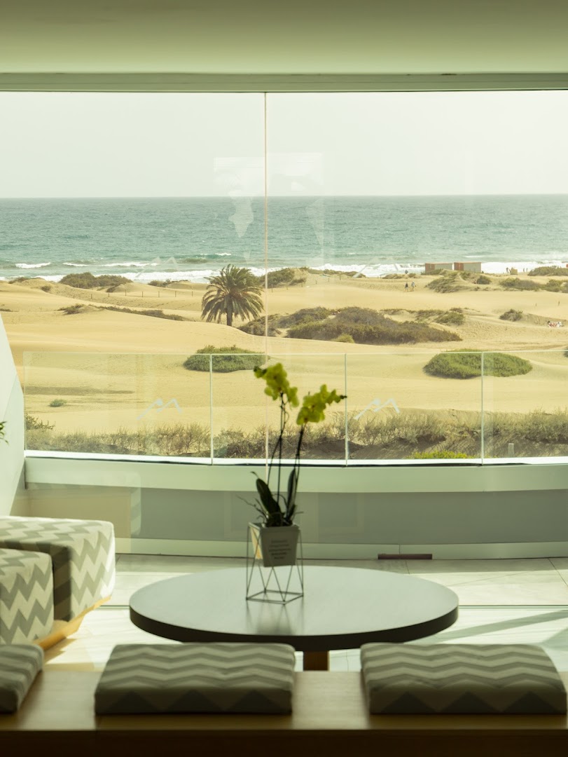 Santa Mónica Suites Hotel atpūtas zona ar skatu uz Maspalomas kāpām un okeānu Grankanārijā — gaišs interjers ar panorāmas logiem