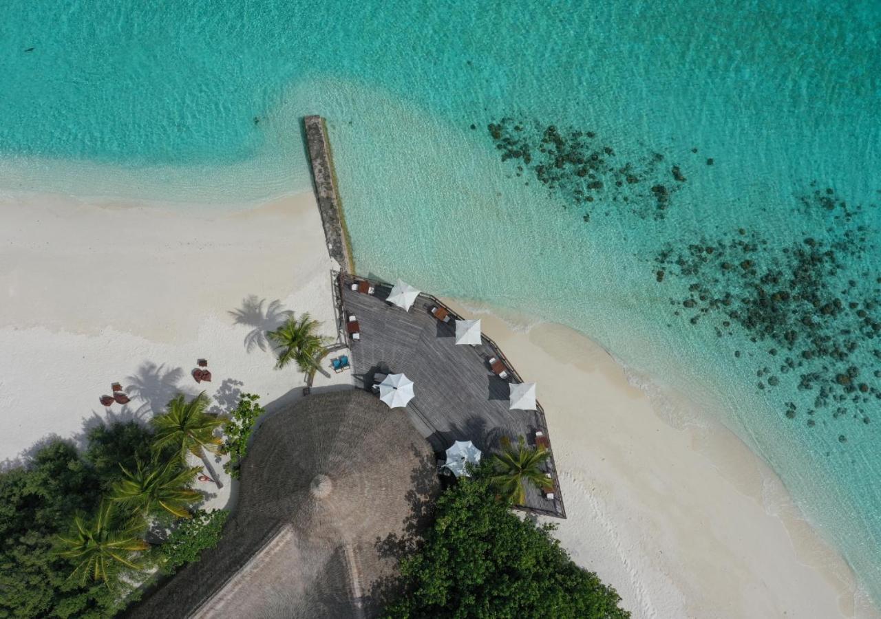 Makunudu Island restorāna koka terase ar saulessargiem un galdiņiem tieši pie tirkīzzilā okeāna krasta Maldīvās