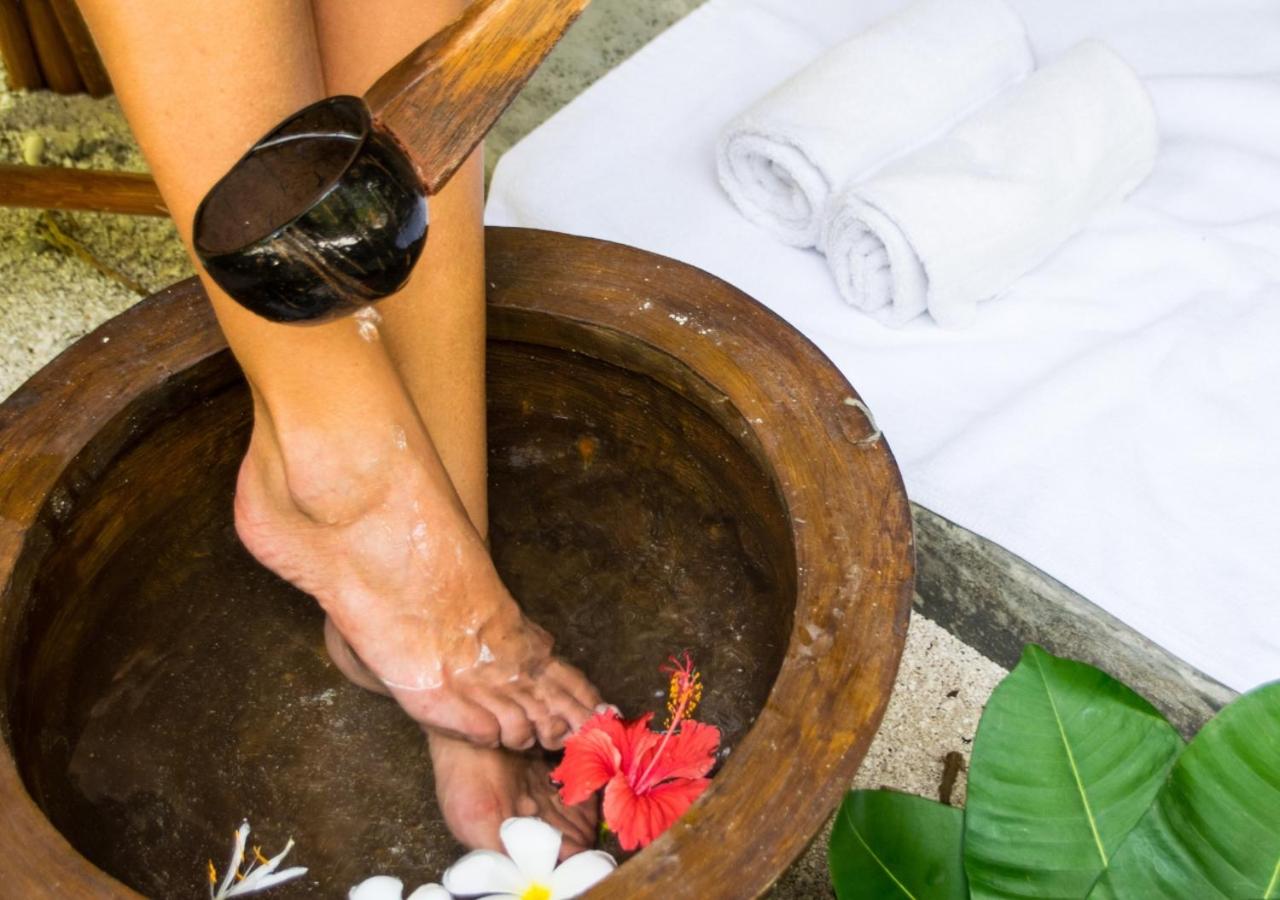 Makunudu Island spa rituāls ar kāju vannu koka traukā, dekorētu ar tropiskiem ziediem un kokosrieksta kausu Maldīvu salās