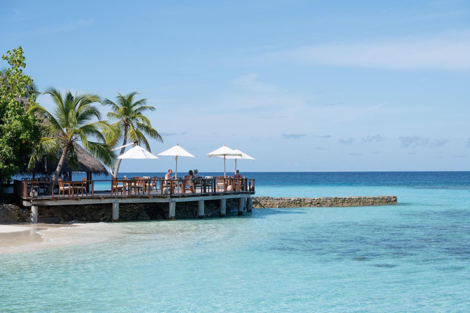 Makunudu Island pludmales bārs un restorāns uz koka platformas pie tirkīzzila ūdens un palmām Maldīvu salās