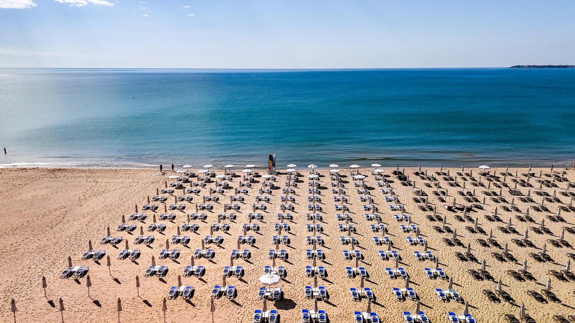 Sentido Bellevue Beach privātā pludmale ar simtiem sauļošanās krēslu un saulessargu pie zilās Melnās jūras Saulainajā Krastā