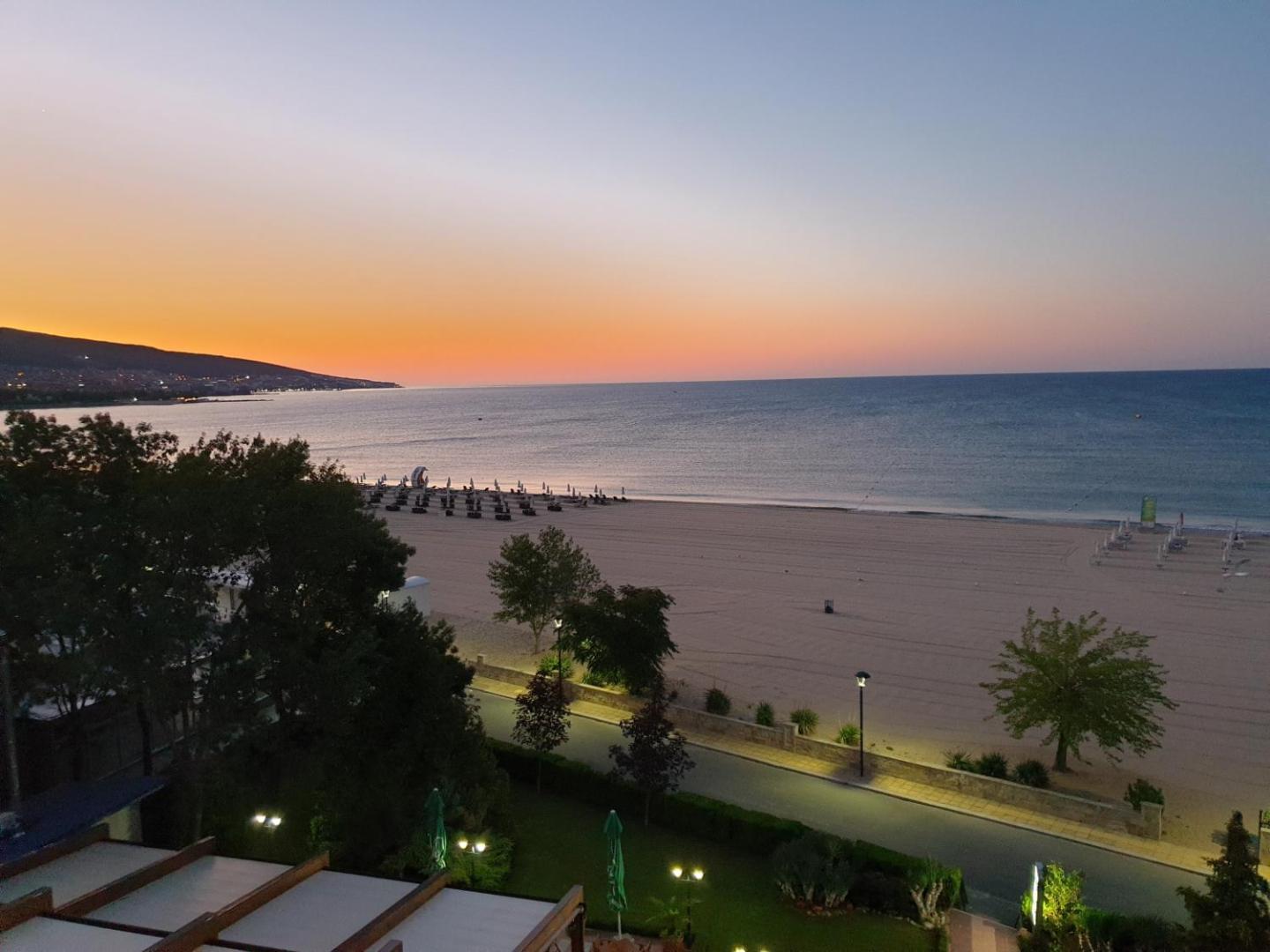 Saulrieta skats no Sentido Bellevue Beach terases uz kluso pludmali un jūras horizontu vakara krēslā