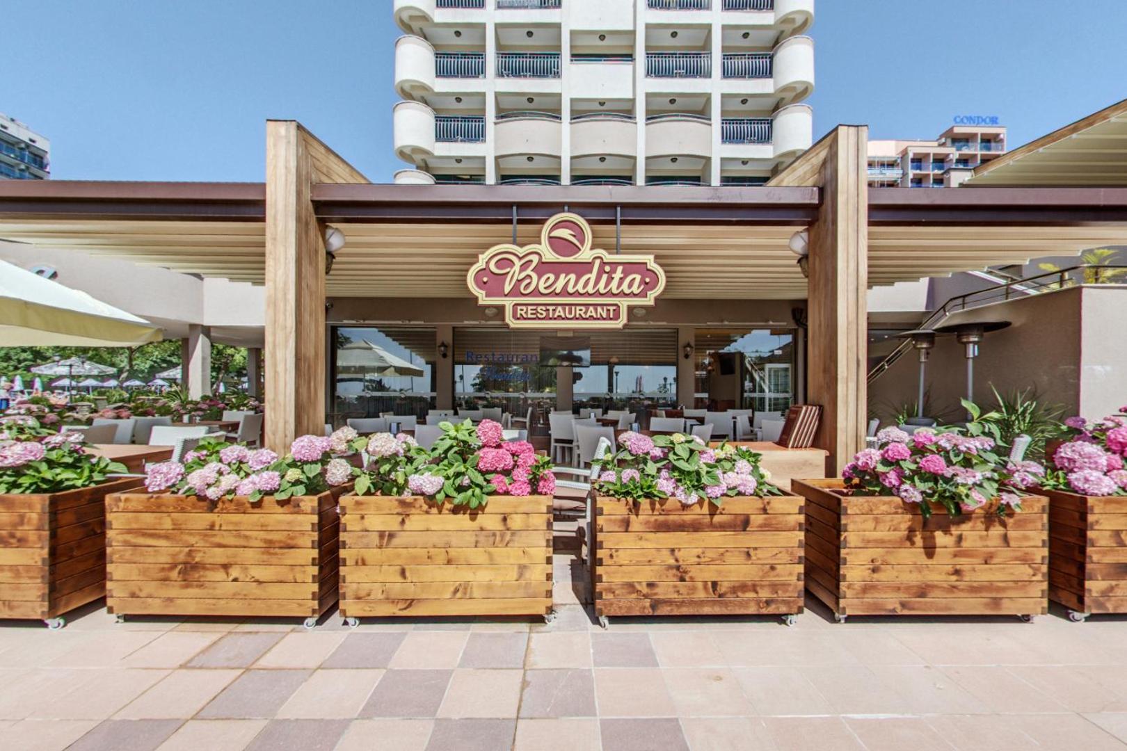 Sentido Bellevue Beach restorāna Bendita āra terase ar ziedu kastēm un galdiņiem pie viesnīcas fasādes