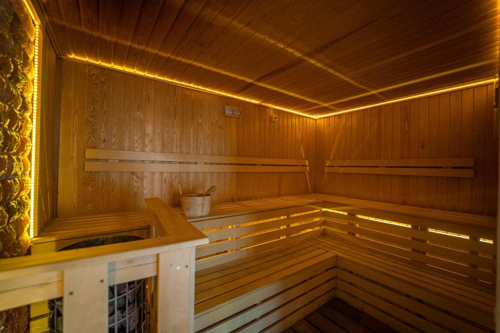 HVD Club Bor viesnīcas spa centra sauna ar koka apdari, siltu apgaismojumu un tradicionālo koka spaini relaksācijai Saulainajā krastā