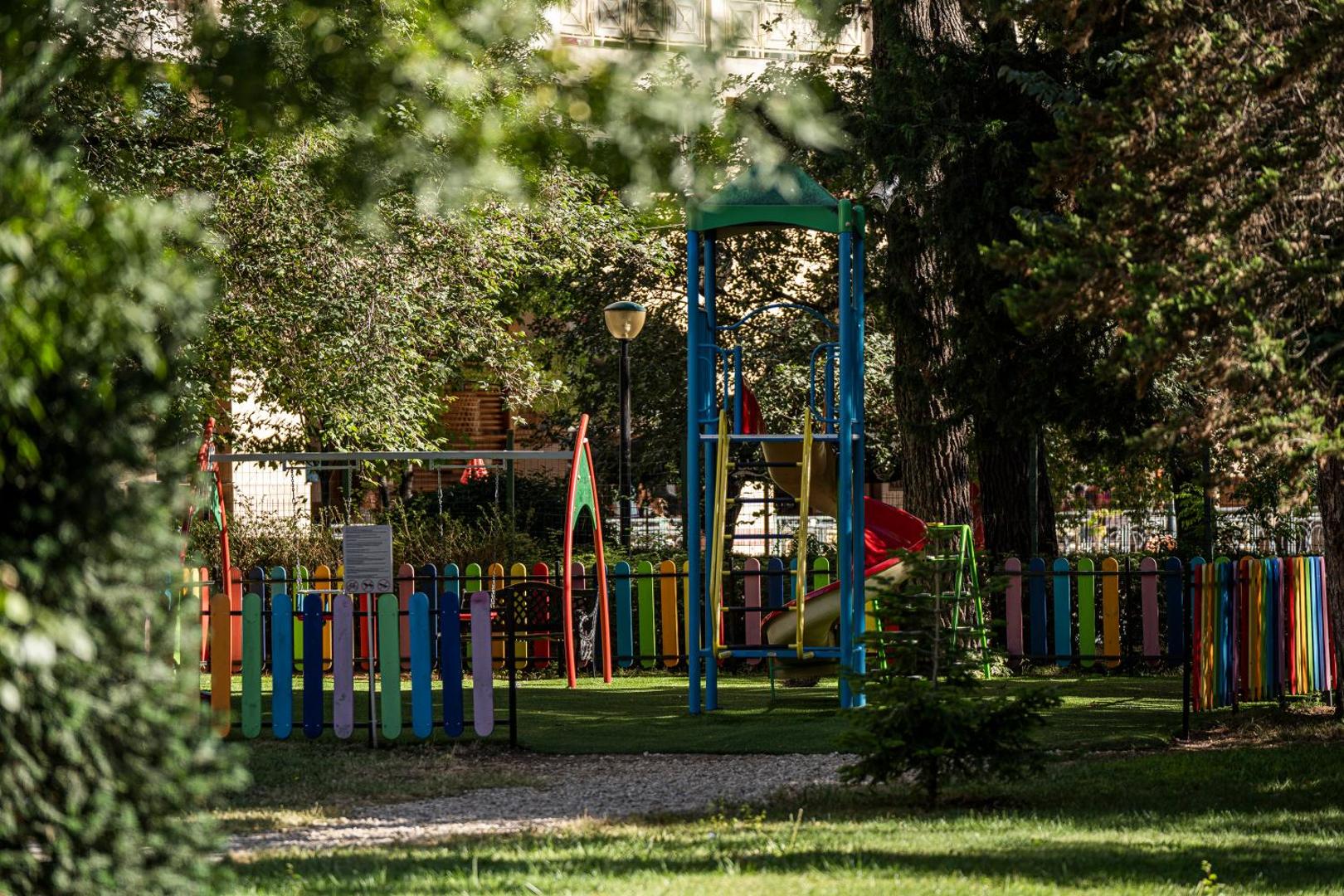 Krāsains bērnu rotaļu laukums ar slidkalniņu un šūpolēm HVD Club Bor viesnīcas zaļajā dārzā
