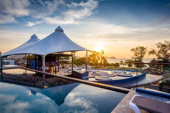 Beyond Patong modernā jumta terase ar baseinu un stilīgām tentu konstrukcijām saulrieta gaismā Puketas piekrastē