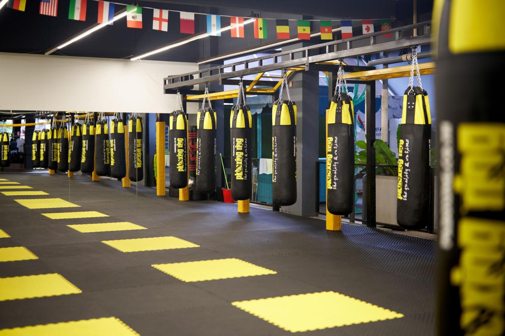 Beyond Patong viesnīcas boksa zāle ar daudziem boksa maisiem un starptautiskiem karogiem Puketā — profesionāls fitnesa aprīkojums aktīvai atpūtai