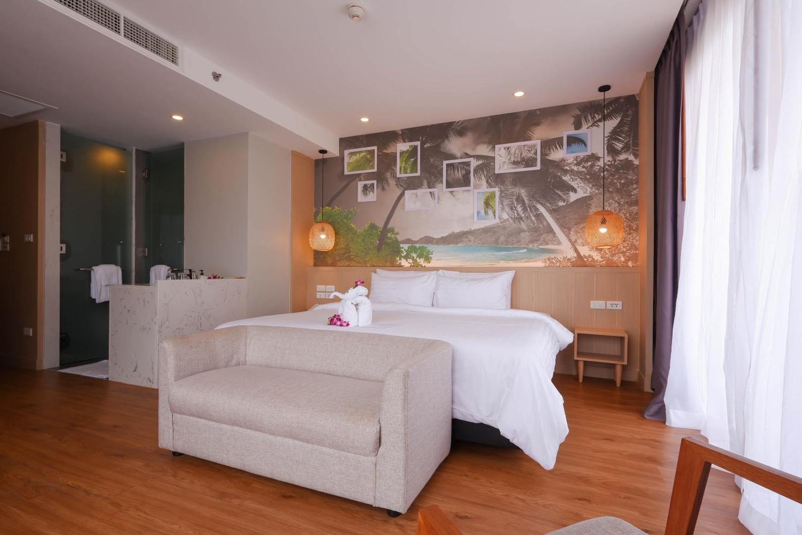 Sea Seeker Krabi Resort numura interjers ar ērtu dīvānu, lielu gultu un tropisku sienas fototapeti Krabi kūrortā
