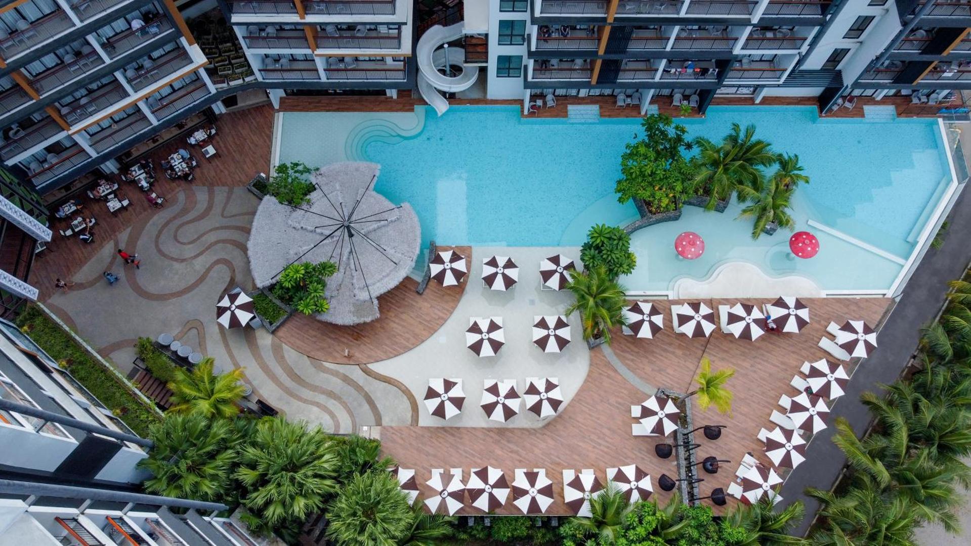 Sea Seeker Krabi Resort skats no augšas uz galveno baseinu, atpūtas zonu ar saulessargiem un bērnu baseinu ar sēnīšu strūklakām