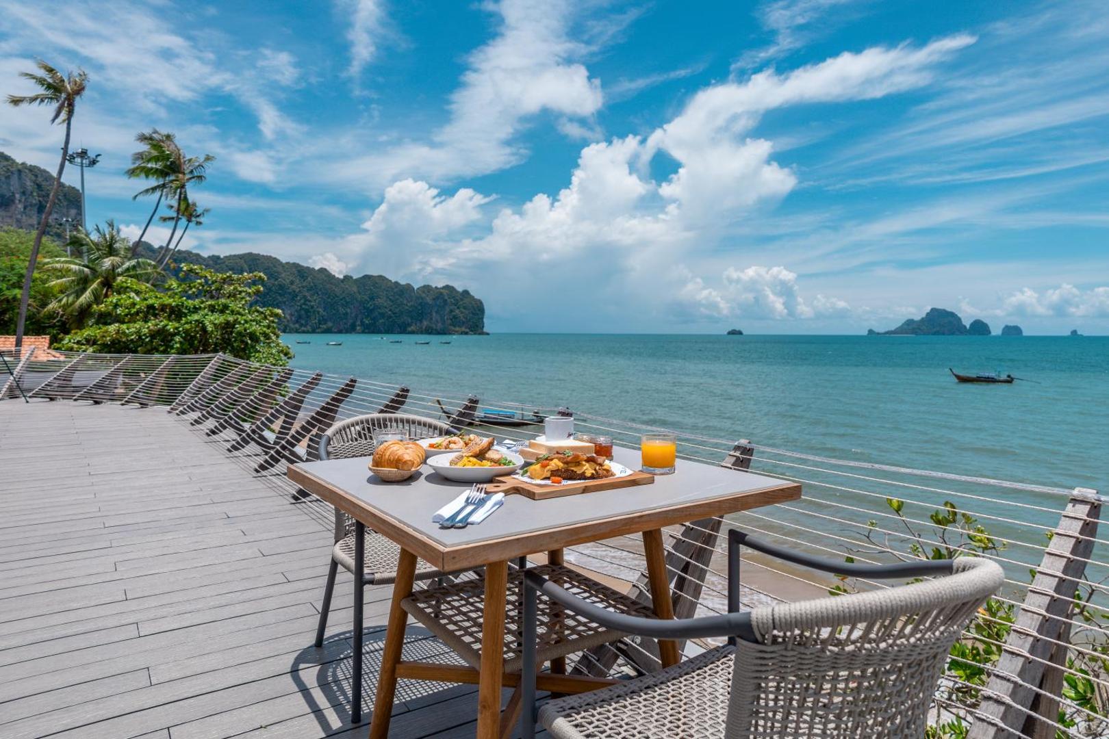 Sea Seeker Krabi Resort restorāna terase ar brokastīm uz galda, skats uz Andamanu jūru un klintīm Krabi provincē