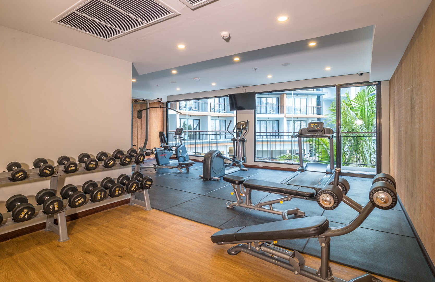 Sea Seeker Krabi Resort mūsdienīgs fitness centrs ar hantelēm, skrejceliņiem un skatu uz viesnīcas iekšpagalmu