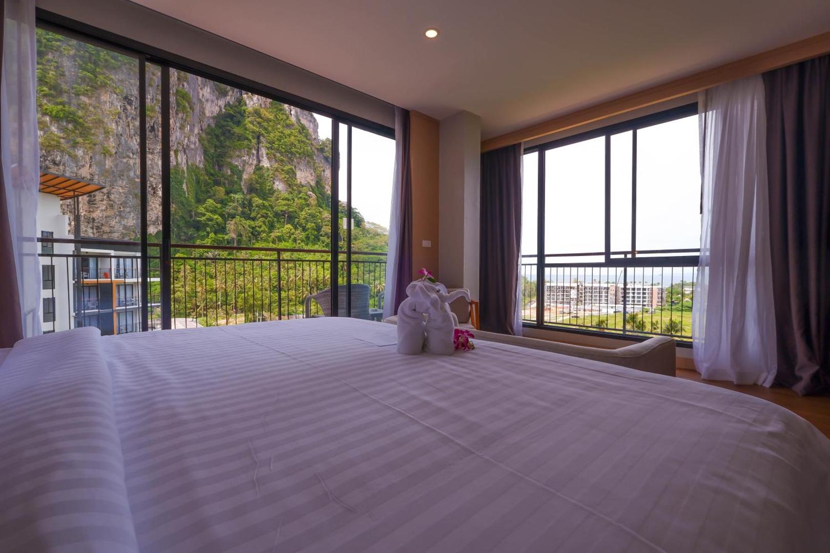 Plašs Sea Seeker Krabi Resort numurs ar panorāmas logiem, no kuriem redzamas klintis un kūrorta apkaime Krabi provincē