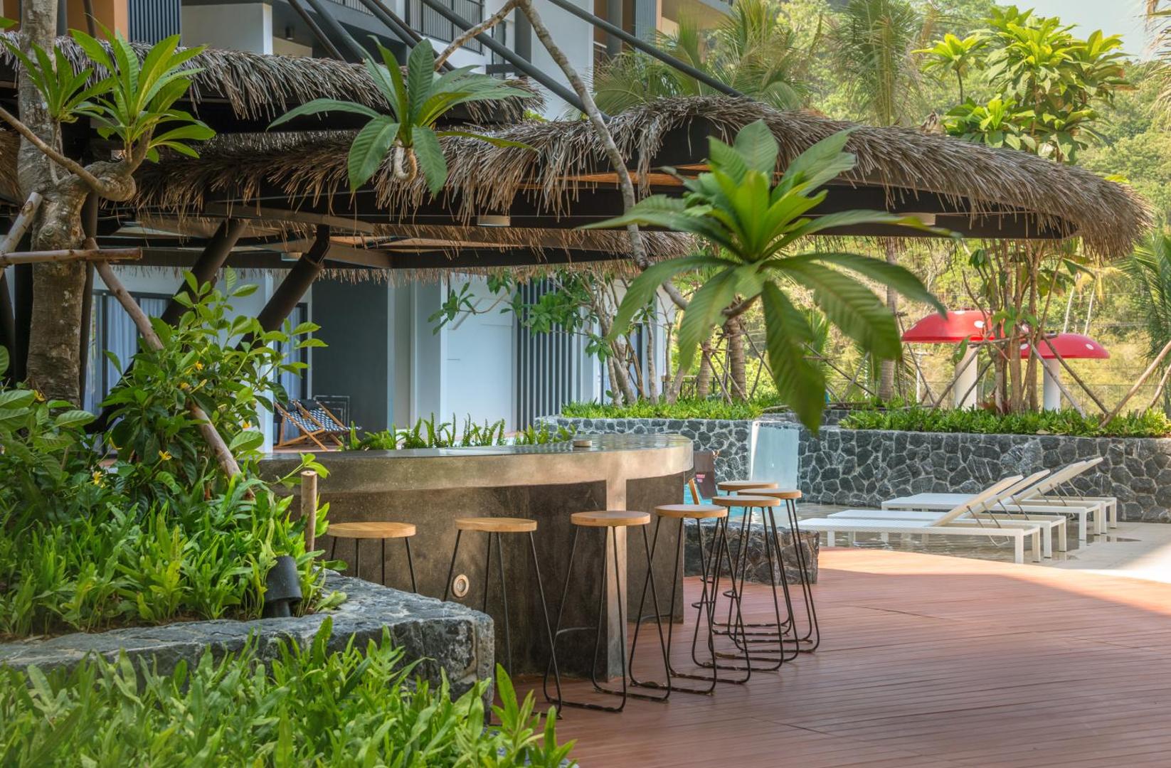Sea Seeker Krabi Resort āra baseina bārs ar tropu augiem, koka krēsliem un salmu jumta nojumi pie baseina