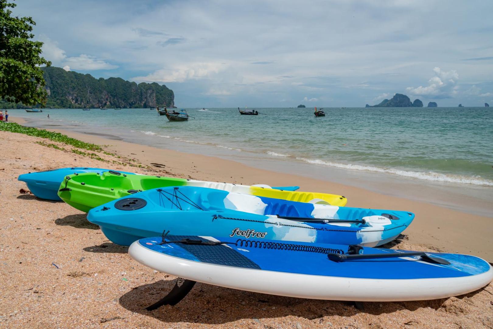 Krāsaini kajaki un SUP dēļi Sea Seeker Krabi Resort pludmales smiltīs pie dzidrā jūras ūdens Taizemē