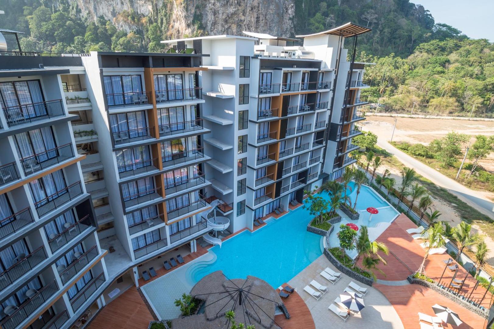 Sea Seeker Krabi Resort modernā ēka ar balkoniem, skats uz baseinu, bērnu slidkalniņu un apkārtējo tropu dabu