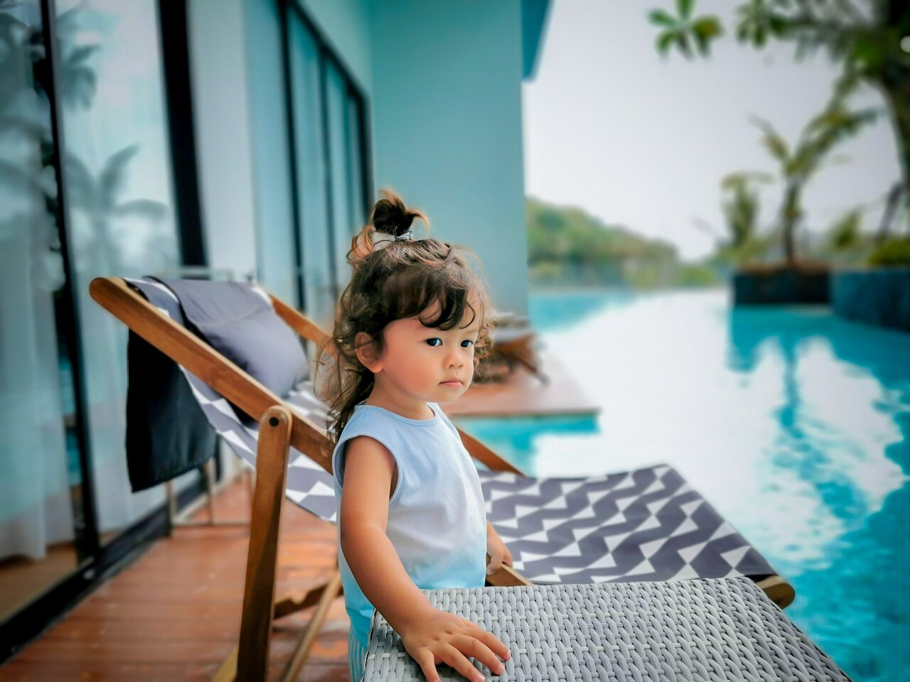 Bērns atpūšas pie Sea Seeker Krabi Resort baseina uz stilīga zviļņa — fonā redzami viesnīcas numuri un tirkīzzils ūdens