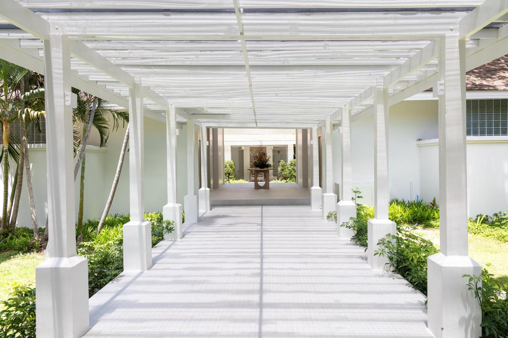 Gaiša un moderna Centara Karon Resort Phuket āra galerija ar baltu koka pergolu un koptu dārzu abās pusēs