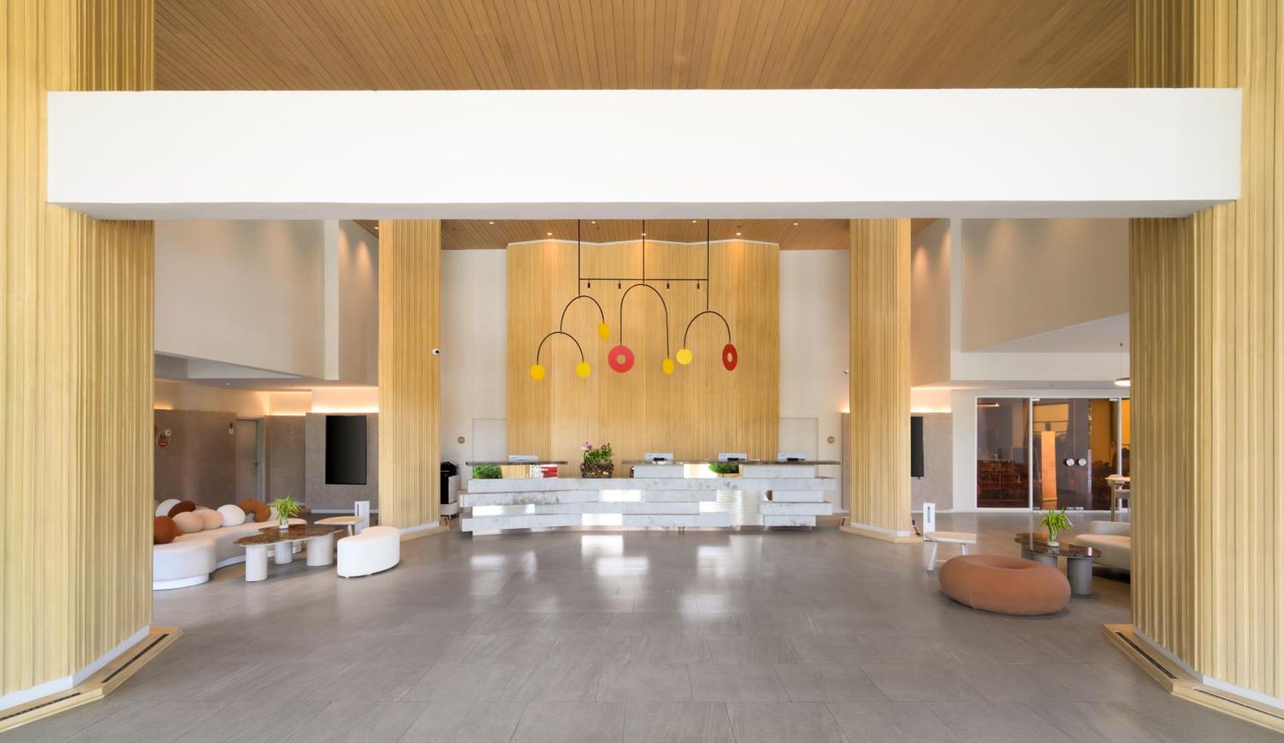 Centara Karon Resort Phuket plašā un gaišā recepcijas zona ar modernu dizainu, koka elementiem un stilīgām atpūtas mēbelēm Puketā