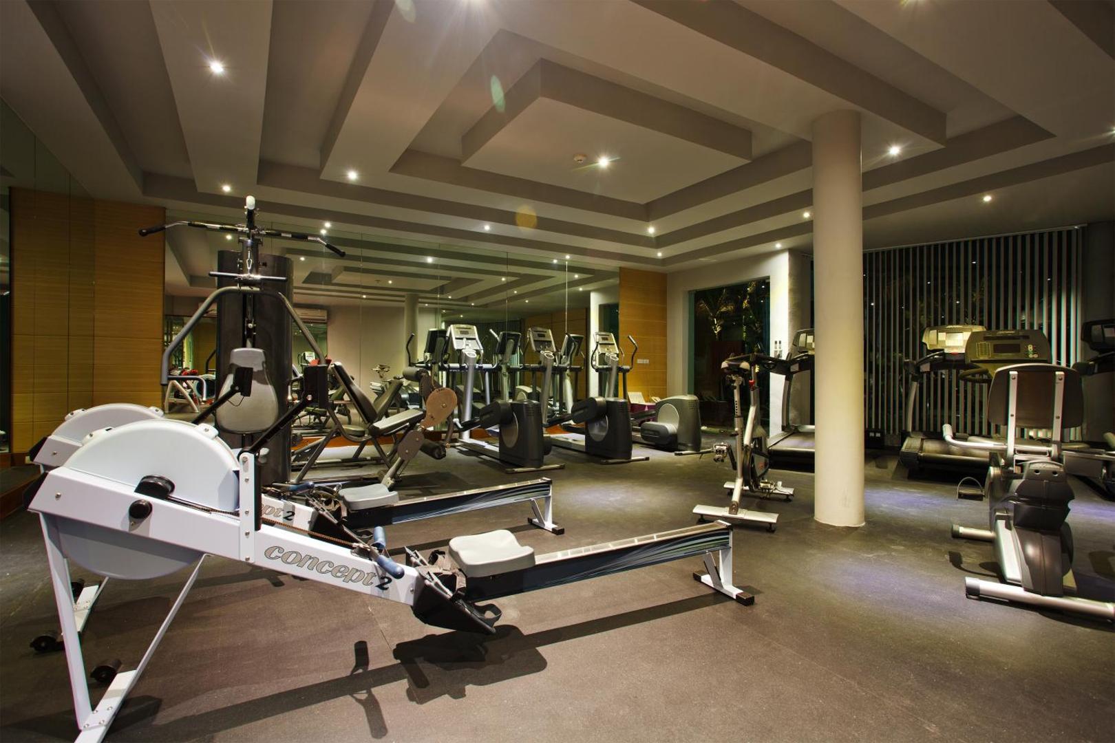 Moderns Mai Khao Lak Beach Resort & Spa fitness centrs ar skrejceliņiem, airēšanas trenažieriem un svariem spoguļu zālē