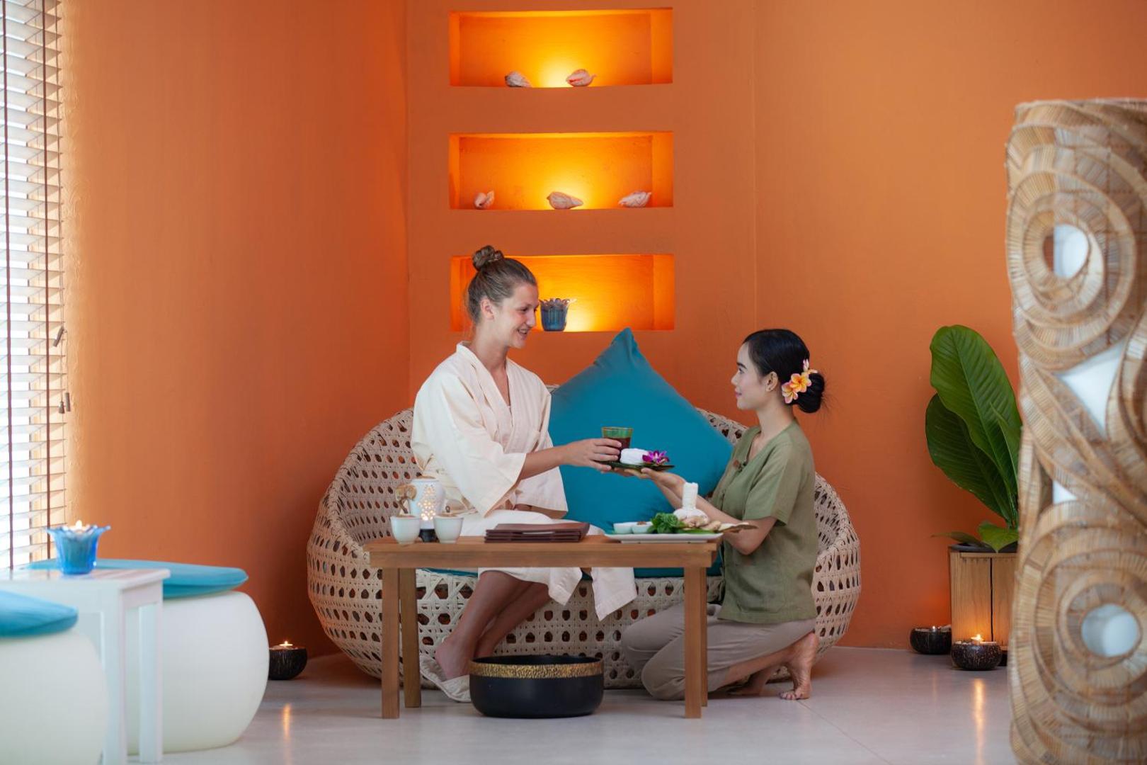 Viesis bauda tēju pēc procedūras Mai Khao Lak Beach Resort & Spa atpūtas zonā kopā ar viesnīcas asistentu