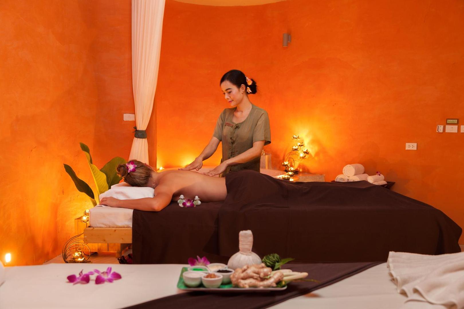 Mai Khao Lak Beach Resort & Spa spa procedūra — terapeite veic muguras masāžu viesim mājīgā telpā ar siltu apgaismojumu