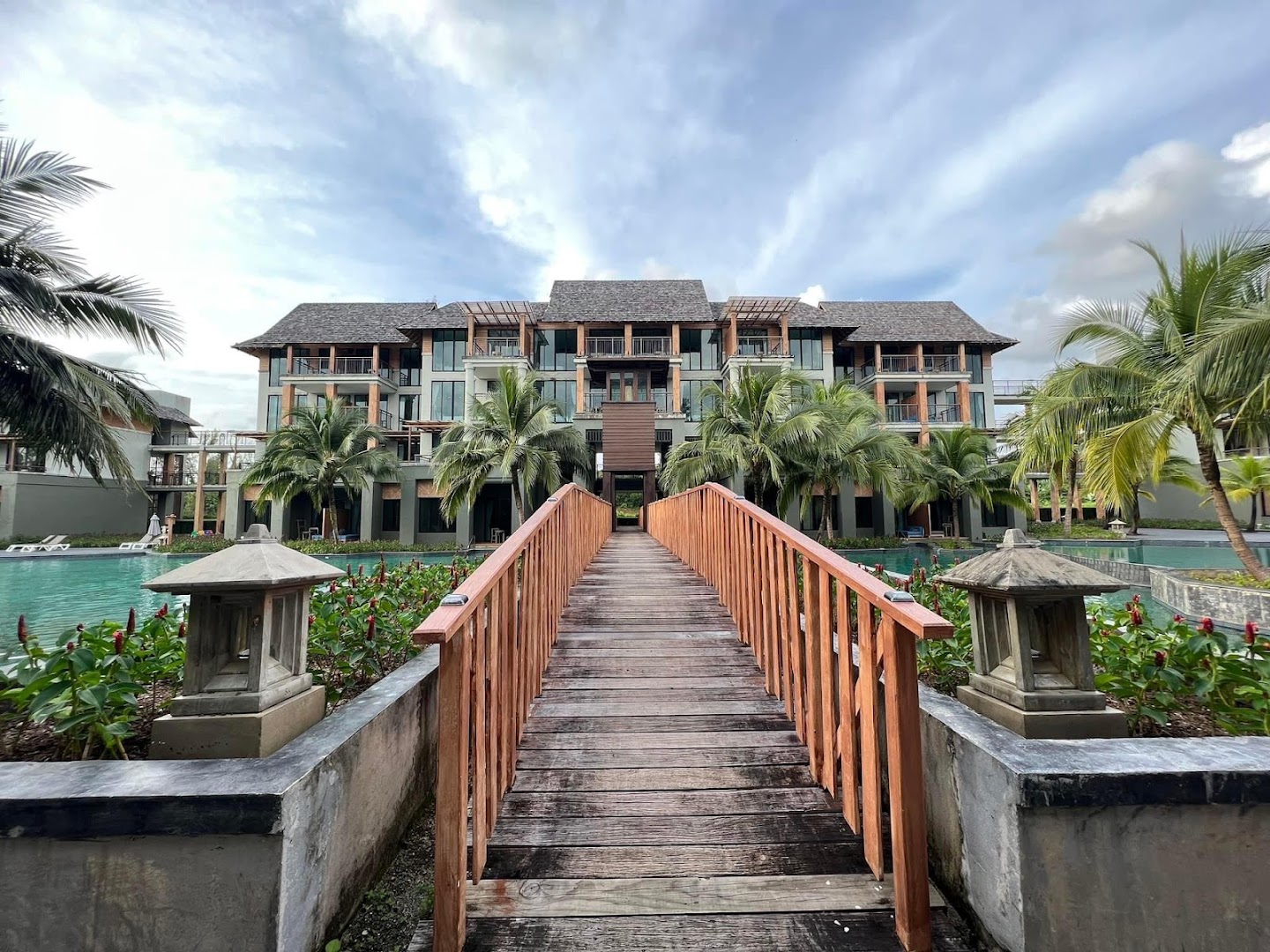 Koka tilts pār baseinu Mai Khao Lak Beach Resort teritorijā, fonā redzama viesnīcas galvenā ēka un palmas