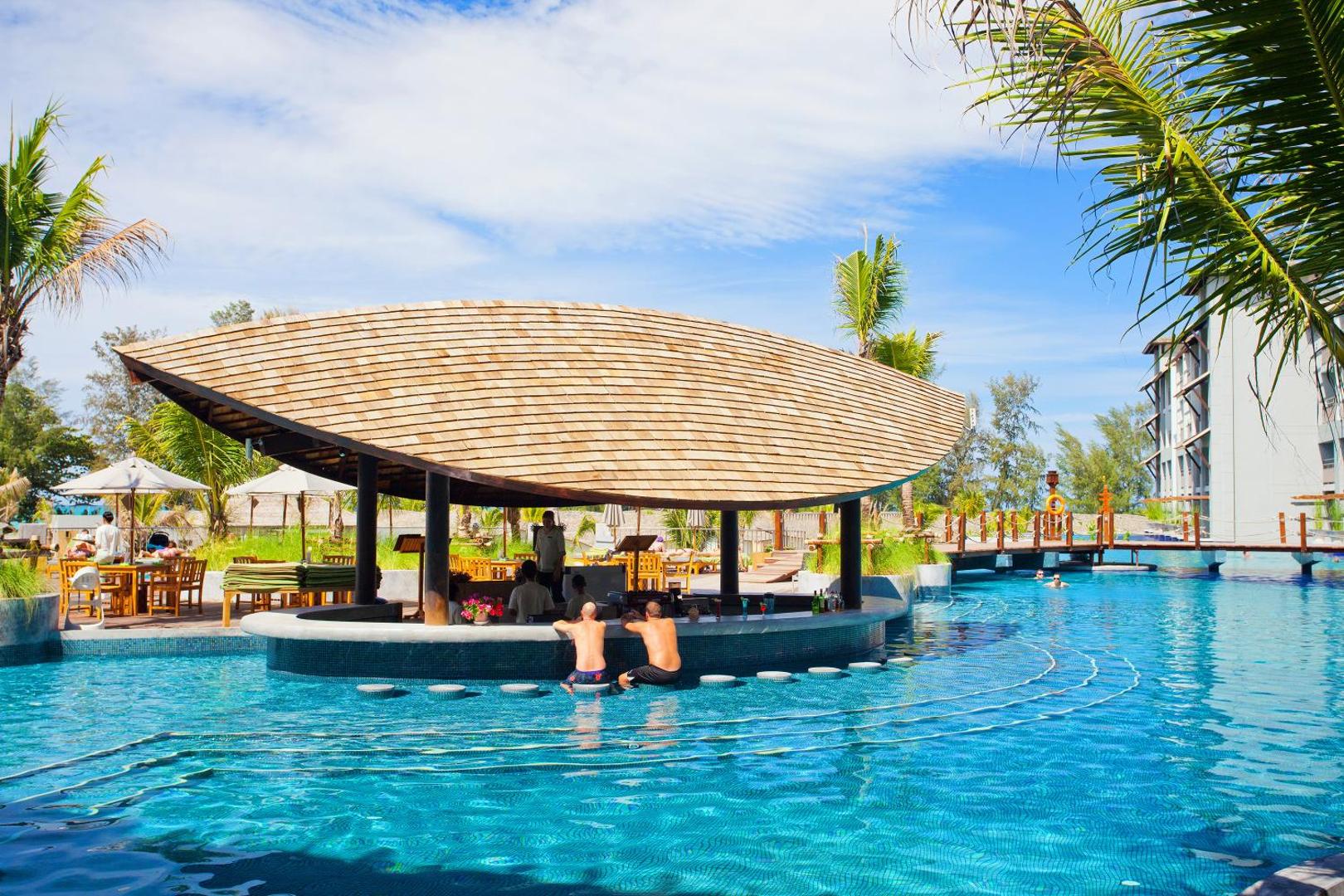 Mai Khao Lak Beach Resort & Spa peldbārs ar unikālu koka jumtu baseina vidū, kur viesi bauda dzērienus ūdenī