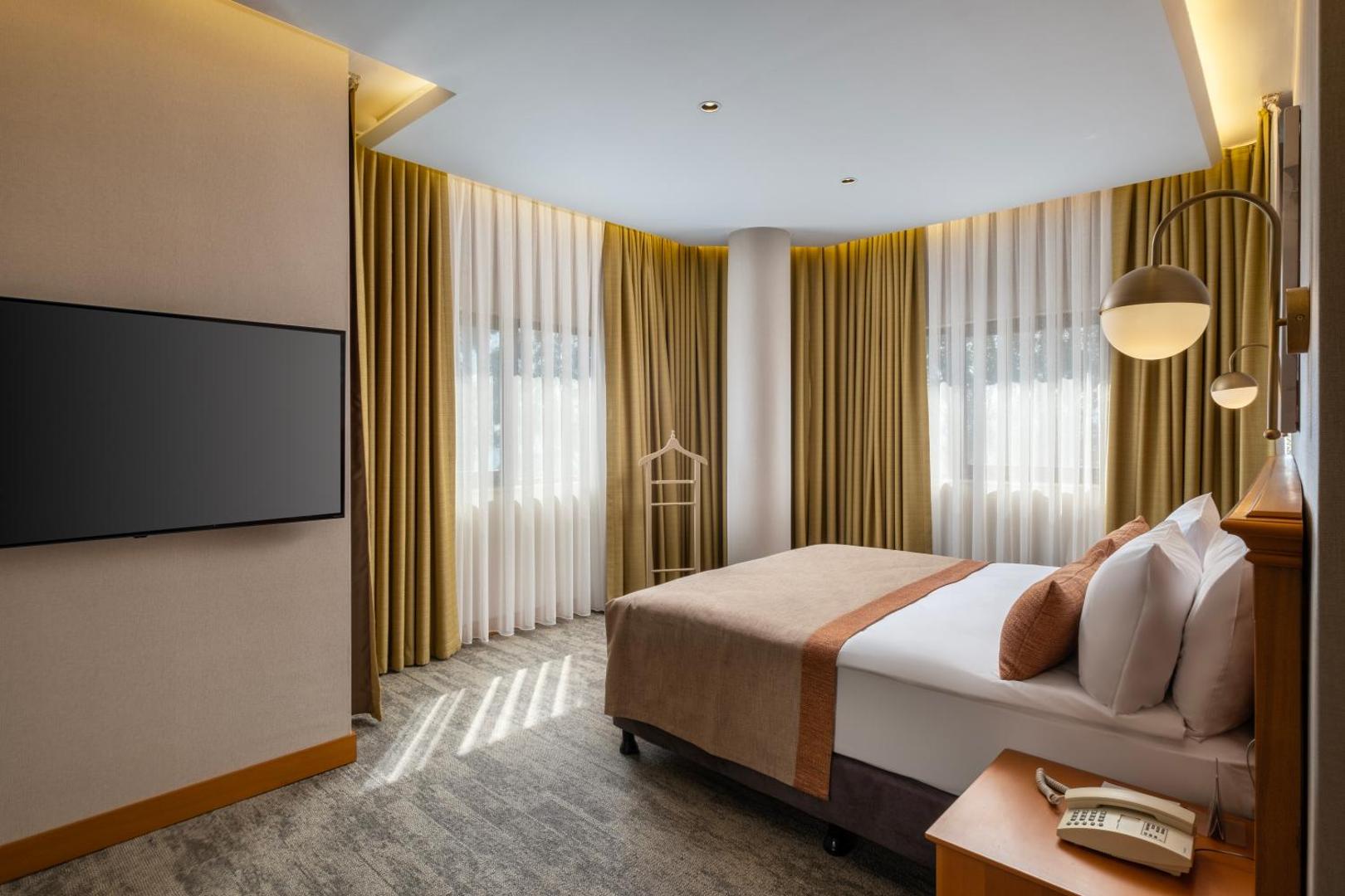 Limak Limra Hotel & Resort elegants divvietīgs numurs ar lieliem logiem un zelta krāsas aizkariem — moderna guļamistaba ar TV