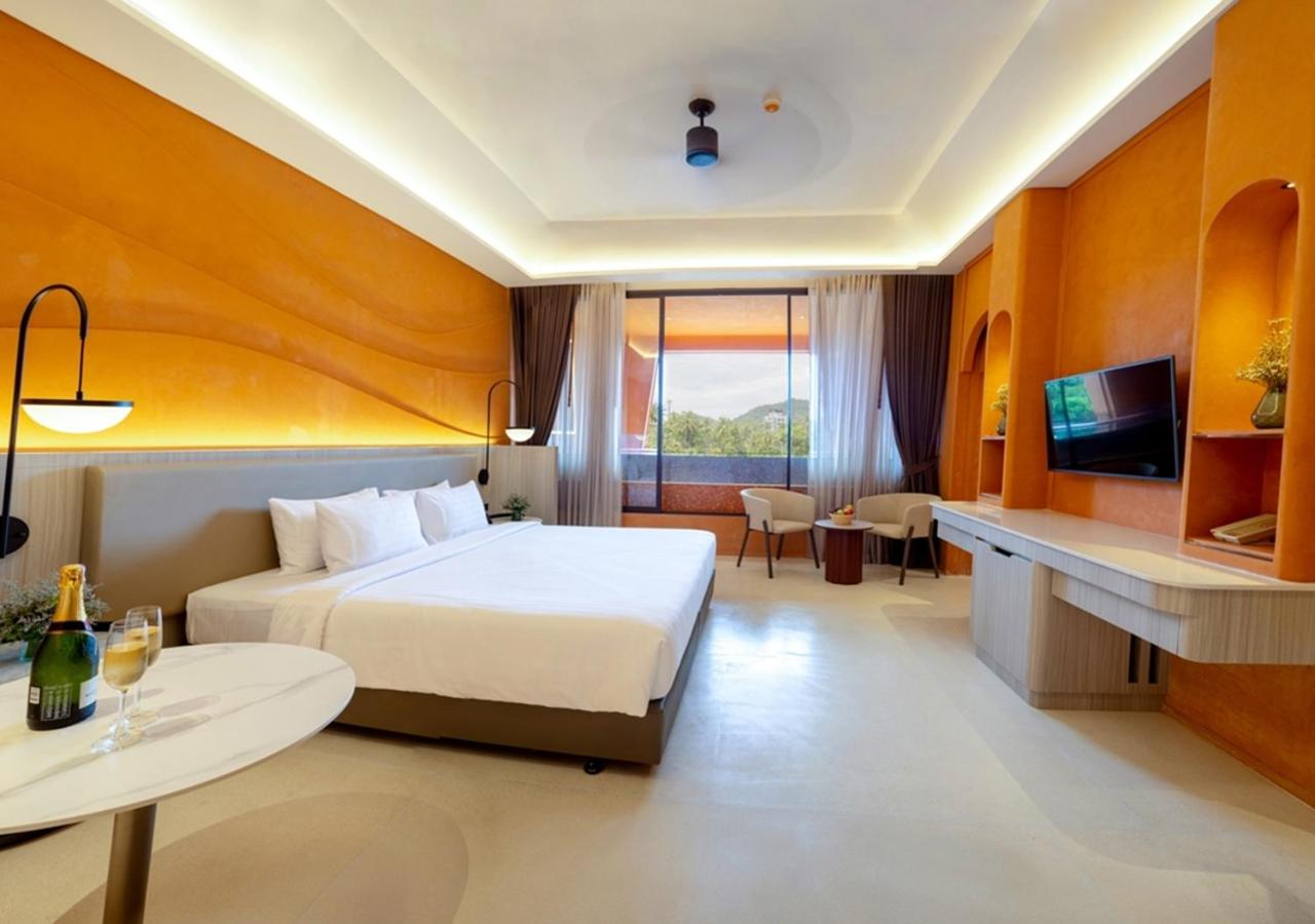 Hotel Adam Krabi moderns numurs ar silti oranžām sienām, lielu divguļamo gultu un panorāmas logu uz tropu dārzu