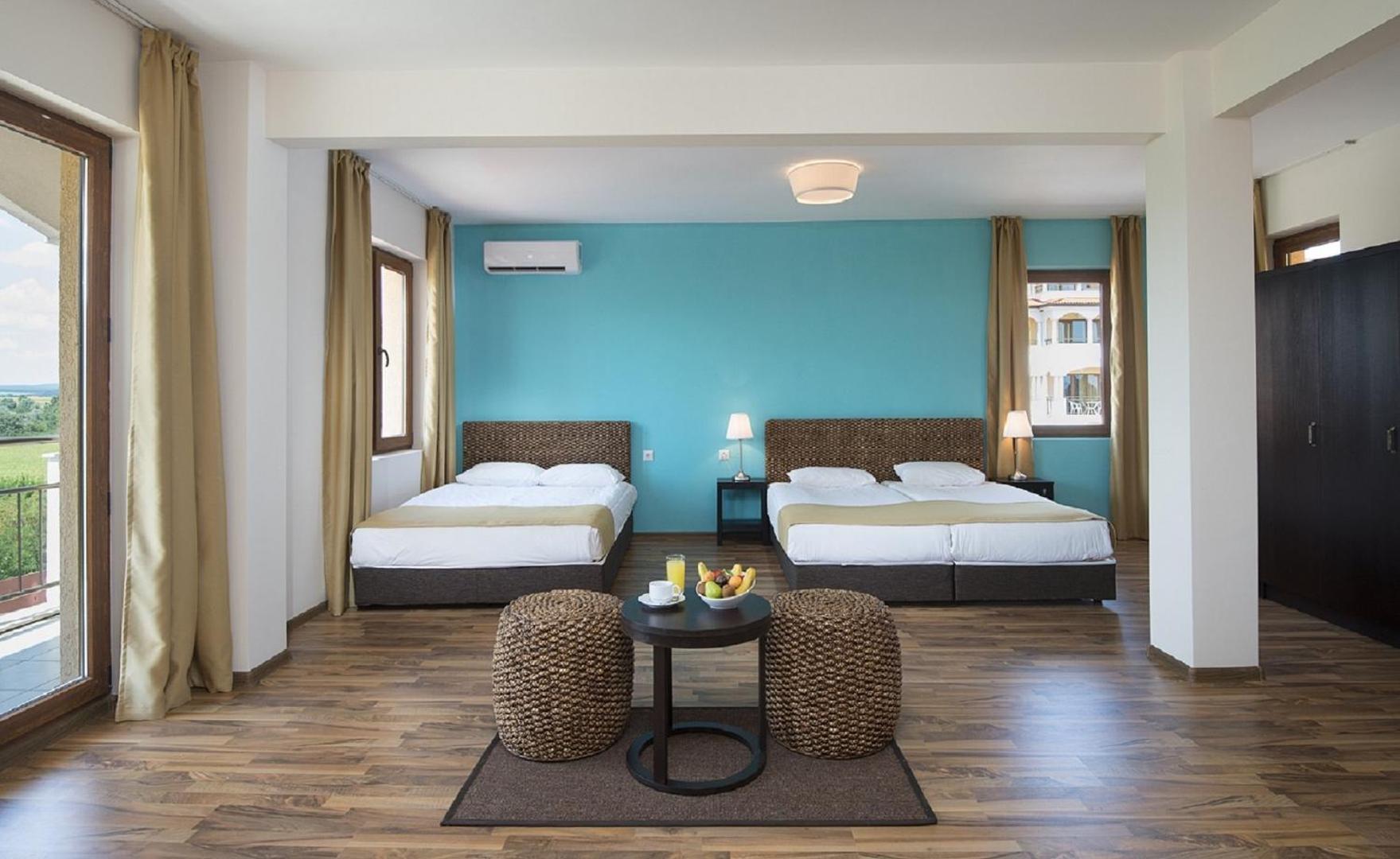 Sunrise All Suites Resort plašs numurs ar divām gultām un atpūtas zonu — debeszila akcenta siena un koka grīdas