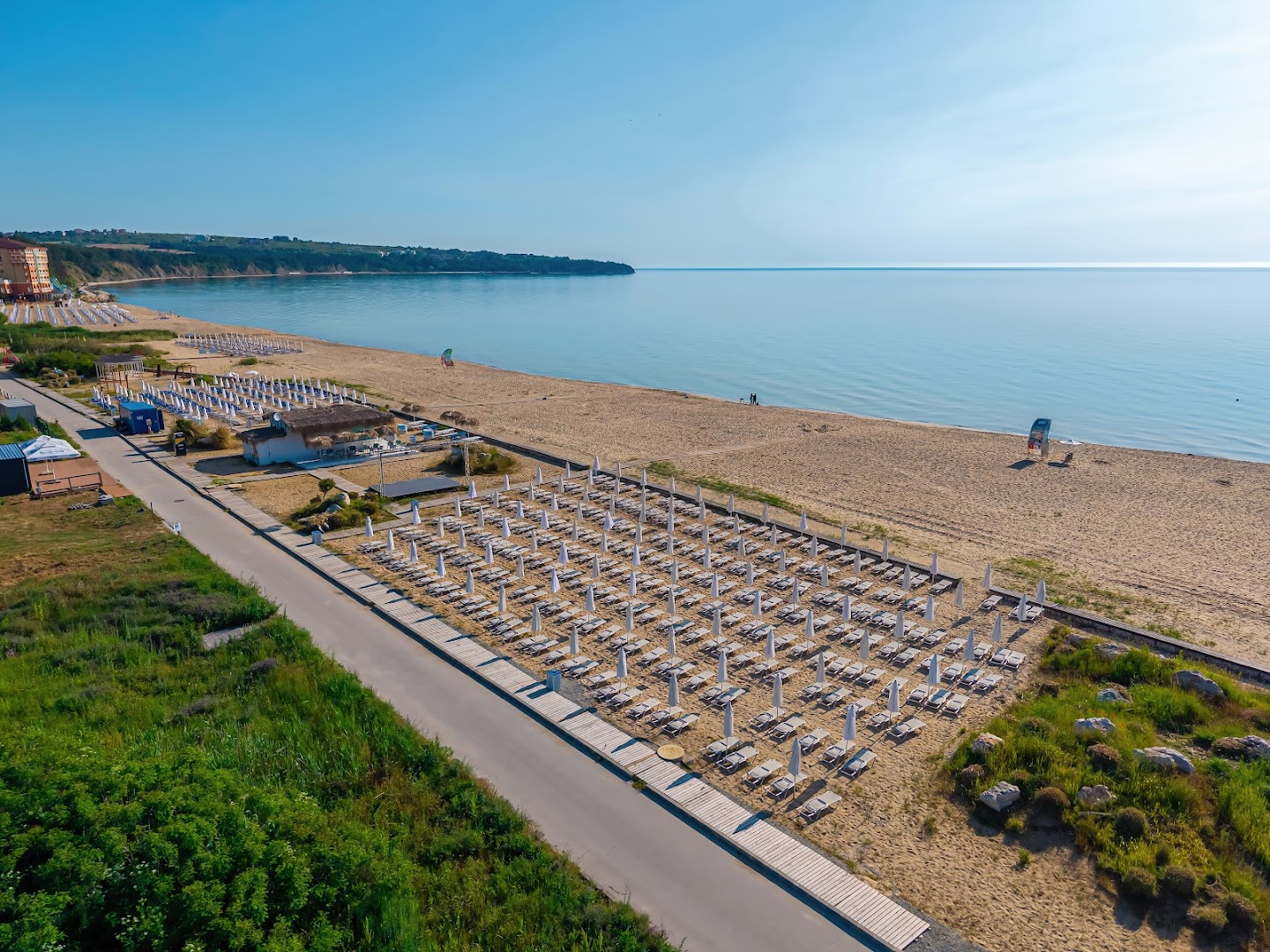 Sunrise All Suites Resort plašā smilšu pludmale Obzorā ar daudziem saulessargiem un guļamkrēsliem pie Melnās jūras dzidrajiem ūdeņiem