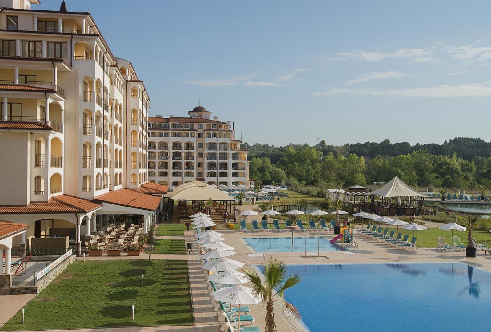 Sunrise All Suites Resort atpūtas zona pie baseina ar saulessargiem un bērnu baseinu ar nelielu slidkalniņu saulainā dienā