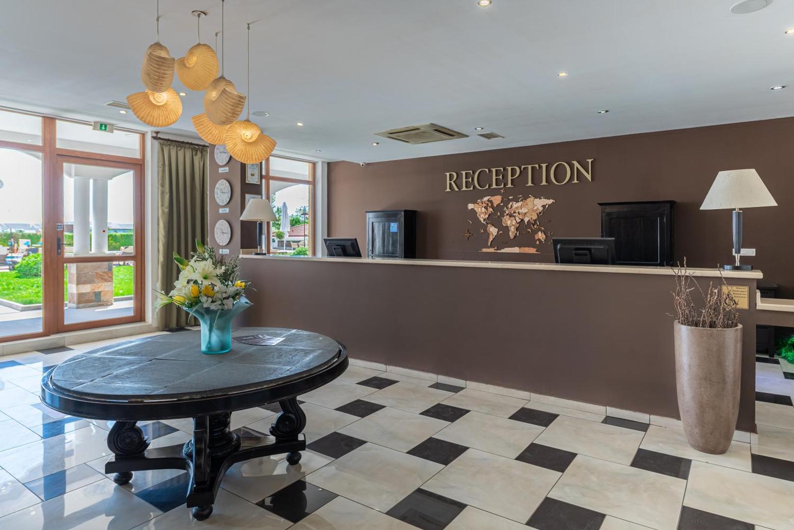 Sunrise All Suites Resort viesnīcas recepcijas zona ar modernu interjeru, pasaules karti pie sienas un dizaina gaismekļiem