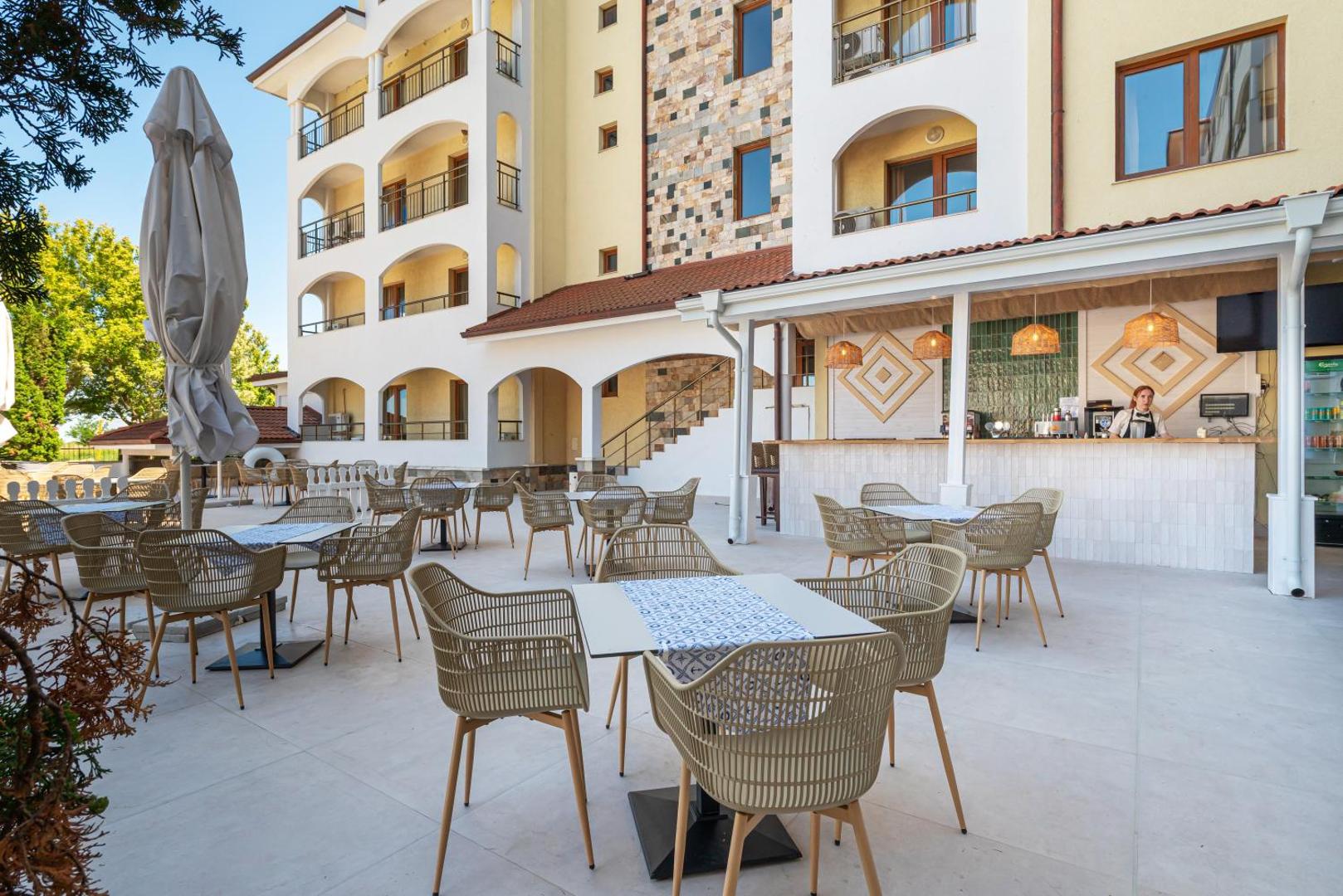 Sunrise All Suites Resort āra bārs un atpūtas zona pie viesnīcas ēkas ar modernām mēbelēm un saulessargiem