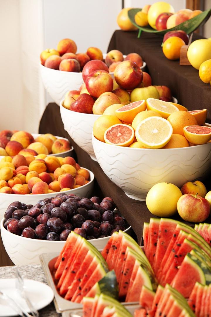 Sunrise All Suites Resort bagātīga svaigu augļu izvēle bufetes restorānā, kur redzami arbūzi, persiki, plūmes un citrusaugļi.