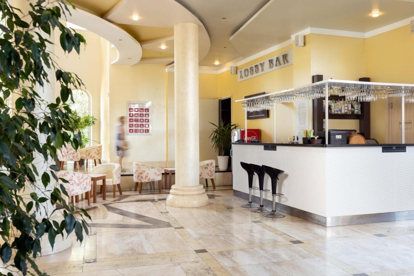 Rome Palace Deluxe lobby bārs ar modernu leti, bāra krēsliem un mīkstajiem atpūtas krēsliem gaišā interjerā